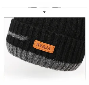 Close-up of black and grey knit winter hat with warm fleece lining and orange leather patch