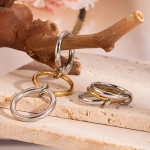 Polished gold and steel interlocking rings displayed on a natural stone and wood stand