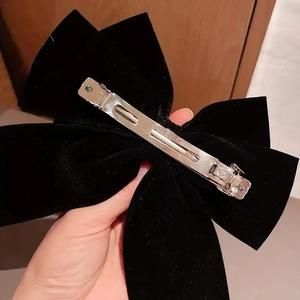Elegant black velvet bow hair clip with silver spring metal fastener in hand