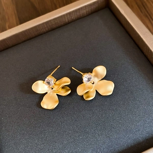Detailed close-up of matte gold flower stud earrings with zircon in a premium jewelry box