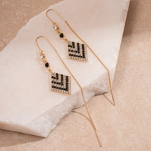 Elegant gold drop earrings with diamond-encrusted geometric rhombus on textured stone