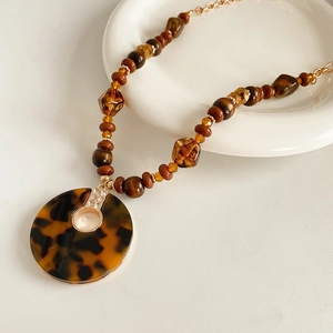 Gros plan du pendentif rond en écaille avec perles d'ambre sur un collier élégant