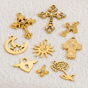 Flat lay of gold plated stainless steel pendants with zircon crosses and sun lock charms