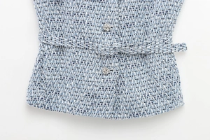 Detail of blue and white tweed vest with embossed silver buttons and matching belt