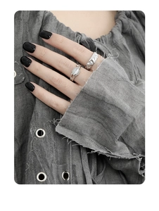 Detailed shot of hammered silver ring set with white gemstone on hand with black nails