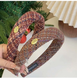 Detail of tweed headbands with gold logo tags in reddish brown and brownish grey tones