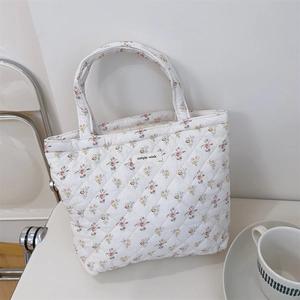 Detail of floral quilted tote bag featuring a stitched 'simple wish' label on fabric