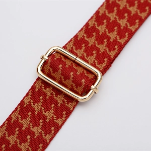 Wide adjustable crossbody bag strap with red houndstooth woven pattern and gold buckle