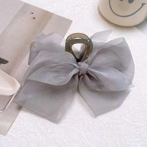 Detail of grey organza bow hair claw clip with semi-transparent plastic shark clip