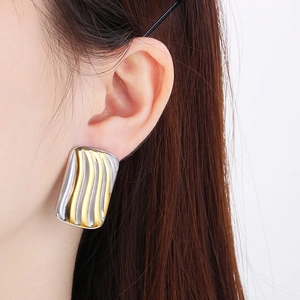 Close-up of two-tone 18K gold plated heart earrings with wave texture on model ear