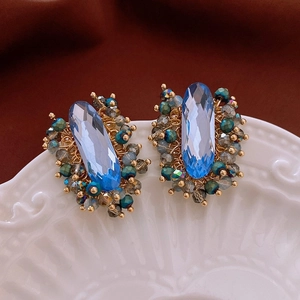 Macro shot of handmade wire-wrapped blue crystal earrings with intricate gold weaving detail