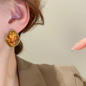 Close-up of a model wearing irregular amber resin earrings with a chunky gold frame