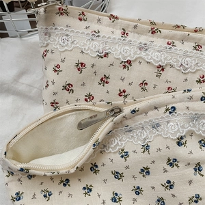 Detail of floral makeup bag with lace trim and smooth metal zipper closure