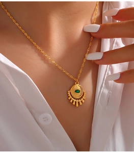 Close-up of a gold twist chain necklace with an eye-shaped pendant and green zircon stone