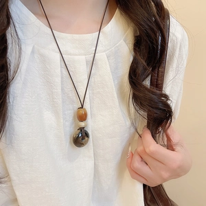 Dettaglio collana con cuore occhio di tigre, perle ambrate e anello marrone strutturato
