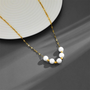 Minimalist gold titanium necklace with five white pearls on elegant white ceramic plate