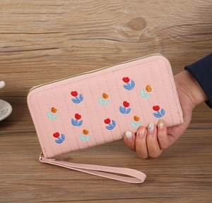 Detail of pink long wallet with floral tulip embroidery and matching wrist strap strap