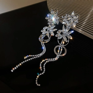 Macro shot of sparkling silver flower tassel earrings with rhinestone details on black background