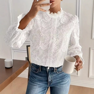 Détail de chemisier en dentelle avec broderie florale et col montant à volants
