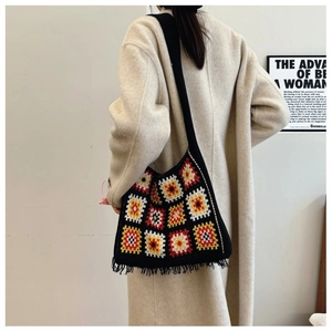 Detailed view of black knitted tote bag with colorful granny square patterns and tassels