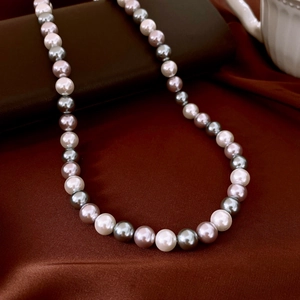 Detail of multi-color glass pearl necklace showing white, pink, and grey beads luster