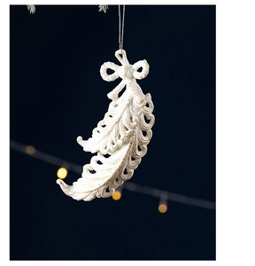 Detailed view of white feather-shaped Christmas ornament with silver glitter and bow