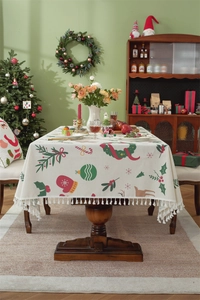Detailed view of beige Christmas tablecloth with red and green prints and tassel edges