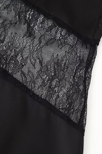 Dettaglio del pizzo nero e della trama in raso lucido sul vestito lungo con schiena scoperta