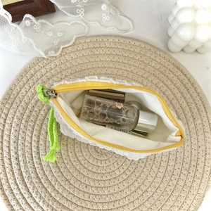 Détail de la pochette blanche à fleurs 3D avec pompon vert et fermeture éclair jaune