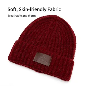 Deep red ribbed knit beanie with ear protection and vintage brown leather patch detail