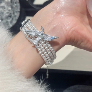 Détail d'un bracelet de perles multicouche avec un pendentif oiseau en zircon brillant