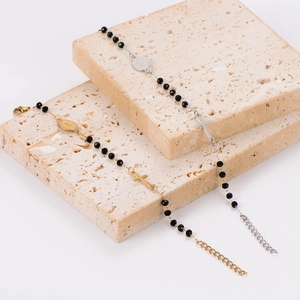 Gold and silver rosary bracelets with black beads and crucifix charms on stone