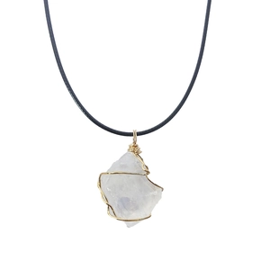 Close-up of raw crystal pendant wrapped in gold wire with a black cord necklace
