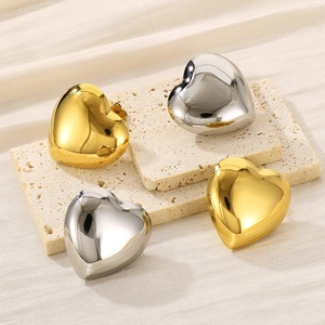 Makroaufnahme von herzförmigen Ohrsteckern in Gold und Silber mit Spiegeleffekt