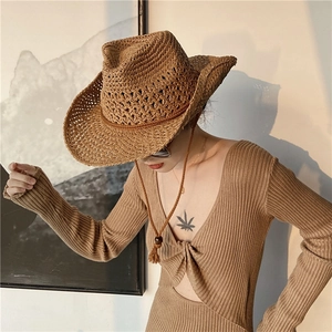 Close-up of a woven straw cowboy hat with ethnic mesh pattern and adjustable chin strap
