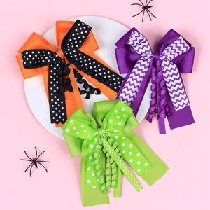 Three Halloween layered bow hair clips with polka dots and stripes on a pink background
