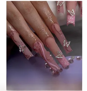 Gros plan de papillons 3D argentés, fleurs roses et perles sur faux ongles pailletés