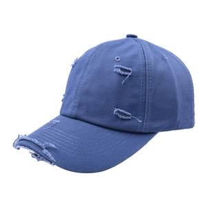 Close-up detail of distressed navy blue cotton baseball cap with vintage frayed holes
