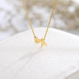 Dettaglio della collana dorata con ciondolo a cuore e lettera A su portagioie bianco