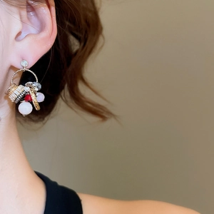 Close-up of golden hoop earrings featuring white and red beads with textured metal rings