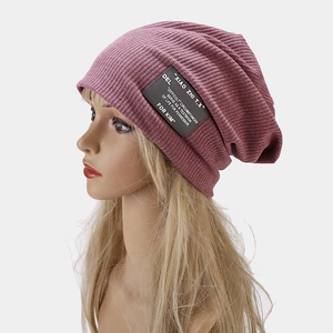 Détail du bonnet slouchy rose poudré avec maille gaufrée et écusson en cuir noir chic