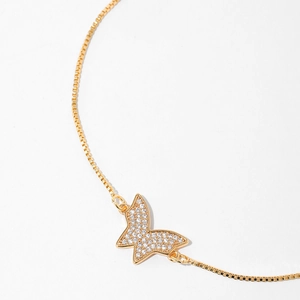 Macro view of gold plated butterfly charm with pavé zircons and delicate box chain