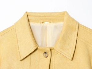 Detail of warm yellow faux suede jacket featuring a classic lapel and amber button