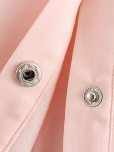 Détail de boutons-pression en métal et texture du tissu rose sur veste de baseball courte