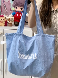Detail shot of a blue canvas tote bag with white lettering against a shelf background