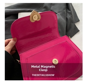 Detailed view of the heart-shaped metal magnetic buckle on the pink patent leather bag