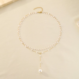Detailed macro view of layered gold necklace with white pearls and elegant Y-shaped pendant