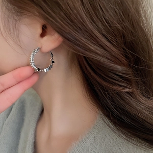 Close-up of irregular silver hoop earrings with zircon accents worn by a model