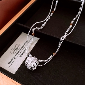 Detailed close-up of double-layer necklace with pearl and hollow pendant in gift box