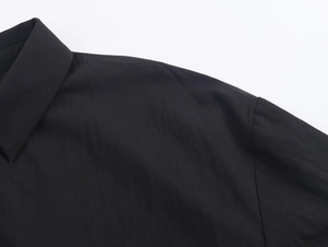 Detailed view of black poplin shirt featuring fine stitching and smooth fabric texture